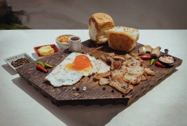 Kızarmış yumurta, kızarmış domuz pastırması ve ballı ekmek ile ahşap kesme tahtasında servis edilen ev yapımı kahvaltı. Sağlıklı gıda konsepti, alanı kopyala, Seçici Odaklanma.