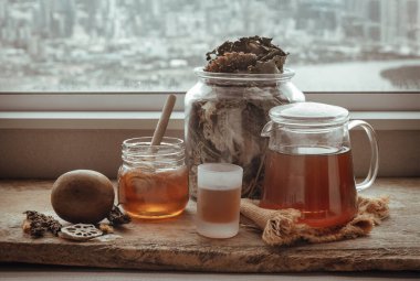 Refreshing with Chinese herbal tea (Jub Lieng) served with honey on old wooden table with city view. Herbal plant and healthy drinks concept, Selective focus.