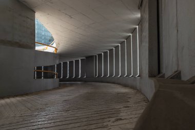 Perspective view of Curving shaped ramp on the high building for spiral indoor car parking lots tower with light channels from cement wall. Copy space, Selective Focus.