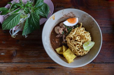 Yoğun çorbada kızarmış sarı yumurtalı şehriye domuz eti, dilimlenmiş bael yumurtaları, dilimlenmiş limon ve kızarmış wonton (Nam tok egg noodles) ile fesleğen ve fasulye filizi ile servis edilen kan eklendi. Tayland eriştesi çorbası ya da Guay tiew reua Tayland 'ın. 