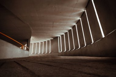 Perspective view of Curving shaped ramp on the high building for spiral indoor car parking lots tower with light channels from cement wall. Copy space, Selective Focus.