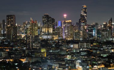 Bangkok, Tayland - 20 Mayıs 2022: Bangkok şehrinin gökdelenlerinin gece parlayan ışıklarıyla güzel manzarası. Seçici odak.