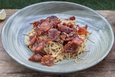 Kızarmış pastırmalı mantarlı carbonara spagettisi ve seramik tabakta rendelenmiş peynir. İtalyan mutfağı, Seçici Odaklanma.