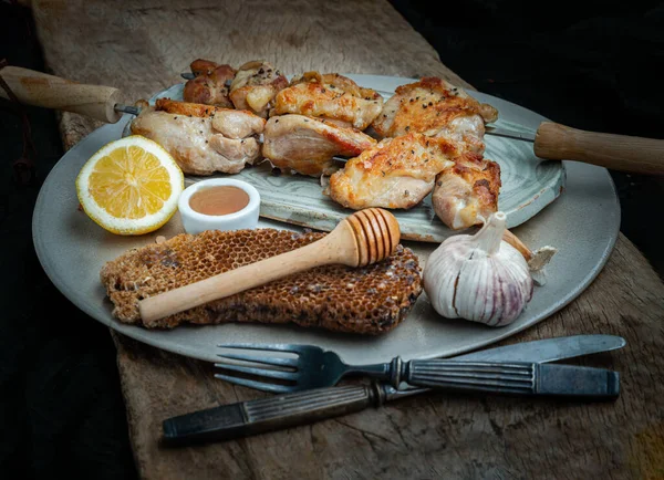 Limonlu ızgara tavuk butları metal şiş ve bal seramik tabakta servis ediliyor. BBQ tavuk şişleri, salamura hazır, seçici odaklanma..