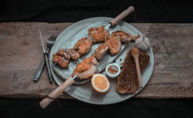 Limonlu ızgara tavuk butları metal şiş ve bal seramik tabakta servis ediliyor. BBQ tavuk şişleri, salamuraya hazır, boşluğu kopyala, seçici odaklanma.