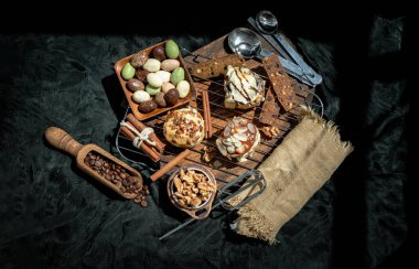 Chocobon (Soft Chocolate Bun) topped with rich cream cheese frosting, Caramel Pecan Cinnamon Roll topped with decadent caramel frosting and pecans and Thai milk tea Almond Minibon with ingredients on dark background. Top view, Copy space, Selective f