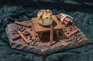 Caramel Pecanbon topped with decadent caramel frosting and pecans served with Cinnamon, Coffee beans on wooden with dark background. Copy space, Selective focus.
