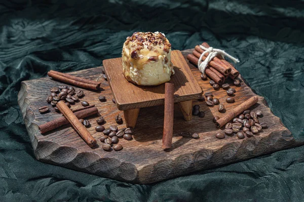 Caramel Pecanbon topped with decadent caramel frosting and pecans served with Cinnamon, Coffee beans on wooden with dark background. Copy space, Selective focus.