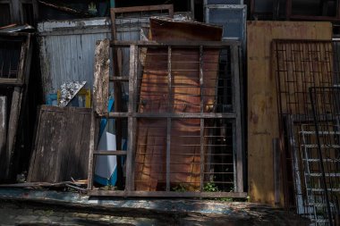 Old frames and shutters from dismantled are stacked against each other front of front warehouse waiting to be sold at auction. No focus, specifically.
