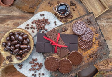 Composition of different Dark chocolate bars and pieces, Melted chocolate and Coffee beans on Old wooden background. Top view, Space for text, Selective Focus.