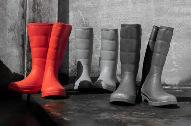 Islak zeminde üç çift yağmur botu ve eski çimento duvar arkası. Metin için boşluk, Seçici odak.