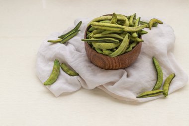 Beyaz arkaplanlı beyaz kumaşla ahşap kasede sağlıklı kavrulmuş bezelye parçaları. Üst görünüm, metin için boşluk kopyala, Seçici Odaklanma.