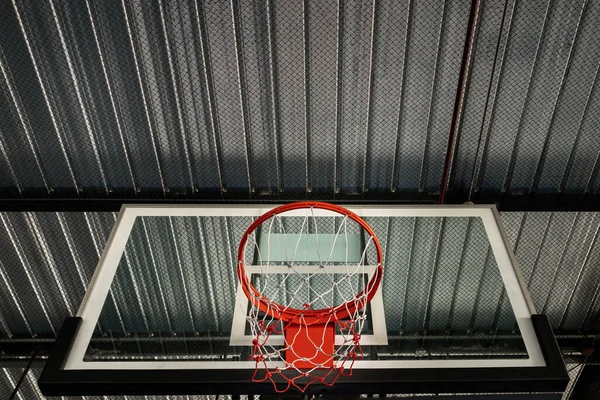泰国曼谷 2020年10月10日 从篮球纤维背板底部看 篮筐红色金属环和白网与体育馆内的天花板金属板相对照 空篮筐 文字空间 有选择的焦点 — 图库照片