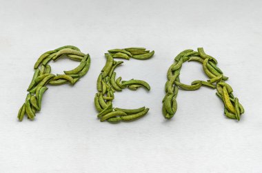 Beyaz arkaplanda bezelyelerden oluşan İngiliz alfabesi. Şekerli bezelyeden yapılmış P E N harfi, metin için alanı kopyala, Seçici Odak.