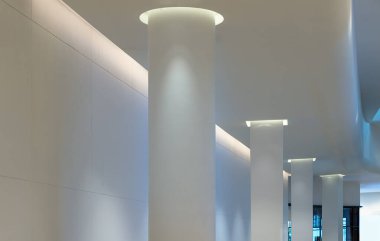 Bangkok, Tayland - 30 Sep 2022: Beyaz yuvarlak sütunlu beton iç mekan, uzun çizgiler halinde ışıklandırma, gölgeyi ve sütunları yansıtıyor. Modern mimariye bakış açısı, Seçici odak.