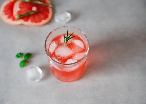 Verfrissend drankje met grapefruitsap en basilicumzaad, een takje rozemarijn, ijsblokjes op een grijze achtergrond.Detox cocktail. Gezond eten. Zomerdrankjes. Rechtenvrije Stockafbeeldingen
