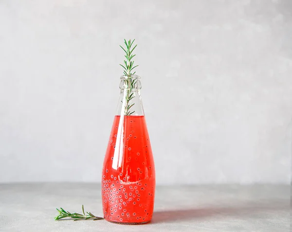 Verfrissende drank met grapefruitsap en basilicumzaad, een takje rozemarijn, ijsblokjes op een grijze achtergrond. Stockfoto