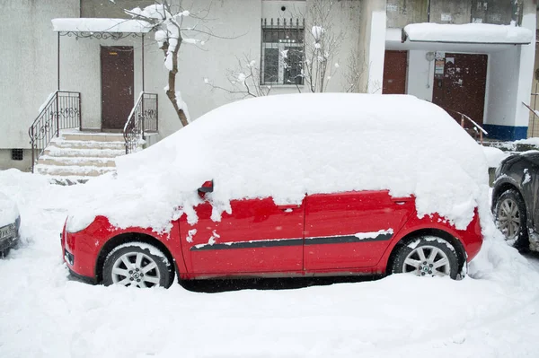 Een auto in de sneeuw in de winter op de binnenplaats van een appartementencomplex. Het probleem van het ontbreken van een persoonlijke garage voor de auto. Sneeuw verwijderen uit de machine, strenge winter Rechtenvrije Stockafbeeldingen