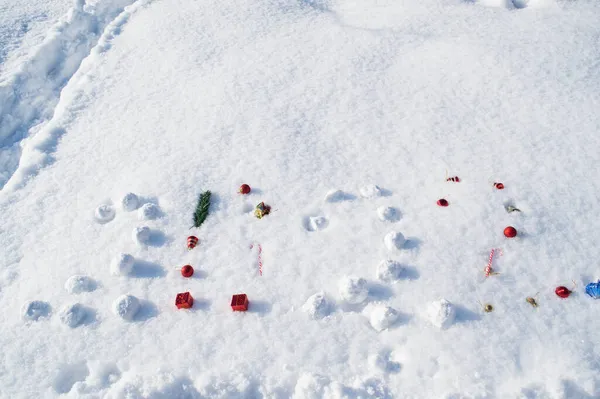 Iscrizione 2022 sulla neve fatta di palle di neve, palle di Natale, bastoncini dolci e stelle. Concetto durante anno nuovo, Natale, vacanze invernali, regali Immagine Stock