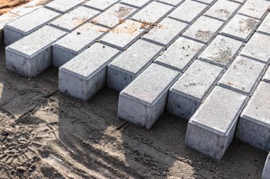 Asfalt tamiri ve kaldırım taşlarının döşenmesi, arka planda fayans küplerinin istiflenmesi. Şehrin yaya bölgesine kaldırım döşeme döşemesi, kum dolgu. Yol fayansları ve kaldırımlar
