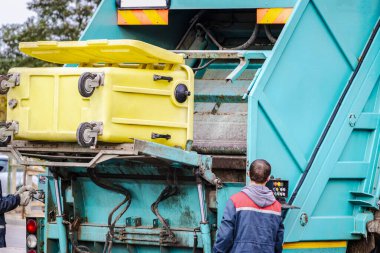 Bir çöp kamyonu yerleşim alanından çöp topluyor. Çöpleri ayrı ayrı toplayın ve yok edin. Çöp toplama aracı