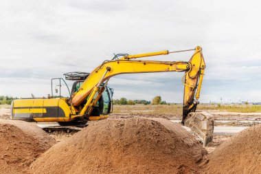 Büyük bir kova ile ağır bir sürüngen kazıcısı inşaat halindeki bir panelin önünde çalışmaya hazırlanıyor. Toprak işçiliği için ağır inşaat malzemeleri. Taş ocağı kazıcısı