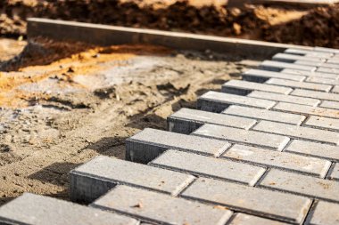 Kaldırım tamiri ve kaldırım döşemeleri hazırlanmış yüzeyde duruyor, arka planda fayans küpleri var. Şehrin yaya bölgesine kaldırım döşemesi döşemek. Taş levhalar ve kaldırımlar