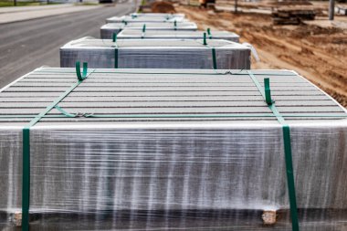 İnşaat alanındaki paletlerin üzerindeki beton kaldırımlar. Beton kaldırım levhaları ve kaldırımların kurulumuna hazırlık. Tamamlanmış eşyalar deposu