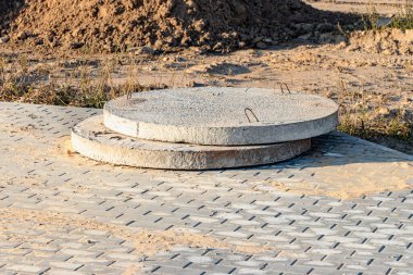 Güçlendirilmiş beton kuyu ve lağım çukurları açık havada uzanıyor. İnşaat alanında güçlendirilmiş beton ürünler. Kanalizasyon kuyuları için endüstriyel üretim tesisleri