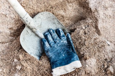 Beton ve işçi eldiveni yapmak için kum yığınına batırılmış kepçe küreği.