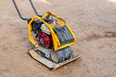 İnşaat alanında titreşimli plakalı bir vibratör. Kaldırım döşemeden önce toprağın sıkışması. Yakın plan.