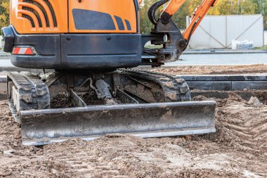 İnşaat alanında mini kazıcı. Toprak işçiliği için kompakt inşaat ekipmanı