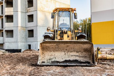 İnşaat alanında elinde kova olan ağır bir yük taşıyıcı. Toprak işçileri, taşımacılık ve malzeme yükleme ekipmanları - toprak, kum, ezilmiş taş