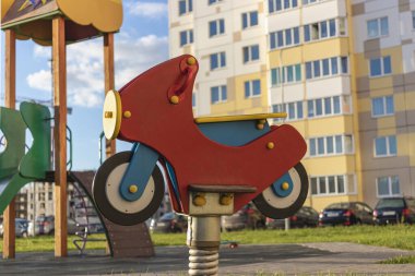 Motosiklet şeklinde çocuk salıncağı. Şehrin yerleşim bölgesindeki bir apartmanın avlusundaki çocuk parkından.
