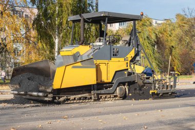 Sonbaharda şehir merkezinde asfalt kaldırım makinesi çalışır. Modern bir şehirde özel ekipman kullanılarak yol yüzeylerinin onarımı