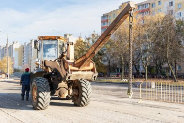 Toplu malların taşınması için ağır bir yükleyici. Sonbaharda modern bir şehrin merkezinde yol onarımı. Malzeme taşımak için ağır inşaat ekipmanları