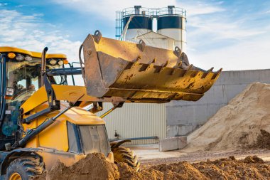 Ön kovadaki bir kazıcı inşaat alanındaki toprağı temizliyor. Toprak işçiliği için inşaat malzemeleri. Yakın plan.