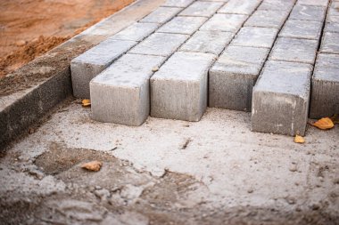 Kaldırım tamiri ve kaldırım döşemeleri hazırlanmış yüzeyde duruyor, arka planda fayans küpleri var. Şehrin yaya bölgesine kaldırım döşemesi döşemek. Taş levhalar ve kaldırımlar
