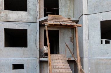 Çok katlı beton bir evin inşaatı. Binanın girişinde güvenli bir rampa. İnşaat alanı güvenliği