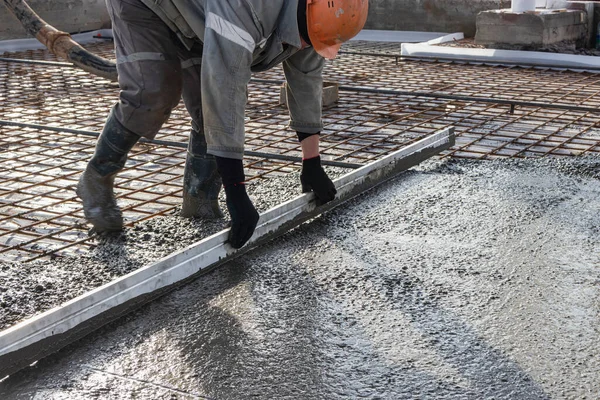 İşçi inşaat alanına zemini dökerken esasen betonu düzleştirir.