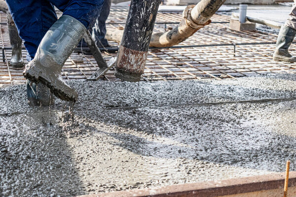 Workers pouring concrete at a construction site. Reinforced floor concreting