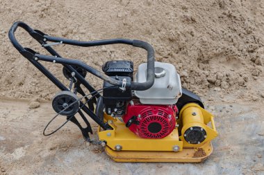 İnşaat alanında titreşimli plakalı bir vibratör. Kaldırım döşemeden önce toprağın sıkışması. Yakın plan.