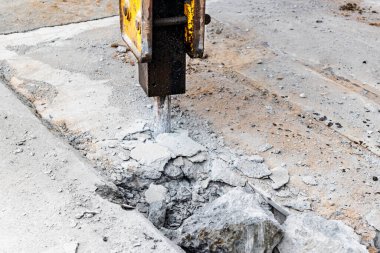 Endüstriyel hidrolik çekiçle ve kazıcıyla güçlendirilmiş beton yapıların profesyonel yıkımı. Üretim alanındaki beton zeminin sökülmesi. Enkaz ve beton kırıntıları.