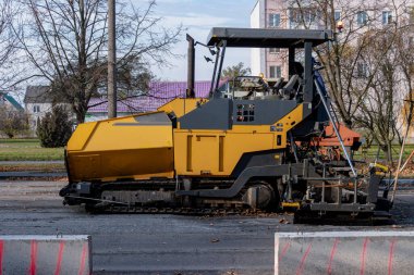 Sonbaharda şehir merkezinde asfalt kaldırım makinesi çalışır. Modern bir şehirde özel ekipman kullanılarak yol yüzeylerinin onarımı