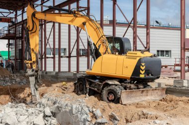 Endüstriyel hidrolik çekiç ve kazıcı kullanılarak güçlendirilmiş beton yapıların profesyonel yıkımı. Metal alaşımlı çubuklar. Beton enkazı ve kırıntıları