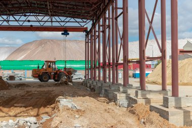 İnşaat alanındaki güçlü bir ön yükleyici güçlendirilmiş beton yapıları söktükten sonra savaşı temizliyor. İnşaat malzemeleriyle toprağı hareket ettiriyor. Kazılar