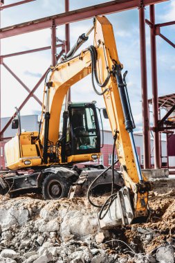 Endüstriyel hidrolik çekiç ve kazıcı kullanılarak güçlendirilmiş beton yapıların profesyonel yıkımı. Metal alaşımlı çubuklar. Beton enkazı ve kırıntıları