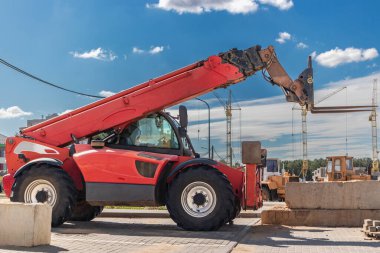 Modern bir yerleşim alanının şantiyesinde teleskopik direkli güçlü bir tekerlek forklifti. Yükleri kaldırmak ve taşımak için inşaat ekipmanları