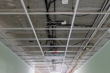 Modern bir ofis binasında sahte tavan kurulumu. Tavanın altındaki iletişim.