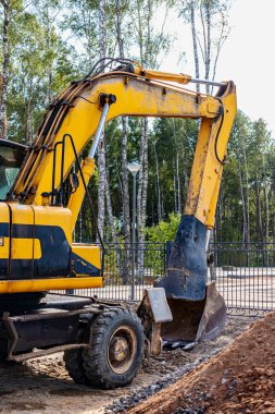Büyük kovalı ağır bir sürüngen kazıcısı işe hazırlanıyor. Toprak işçiliği için ağır inşaat malzemeleri. Taş ocağı kazıcısı. Bölgenin gelişimi